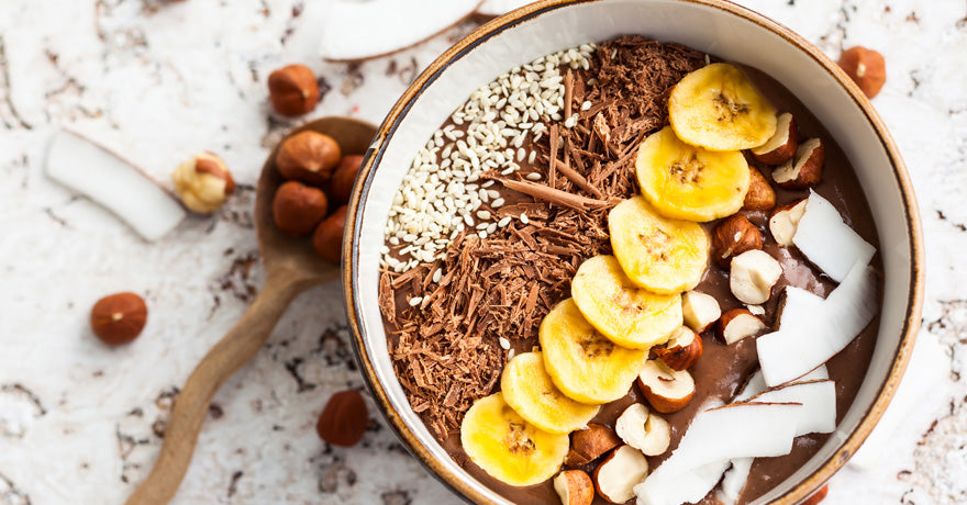 chocolate banana mousse topped banana slices, coconut shreds, hazelnuts and shaved chocolate. top view.