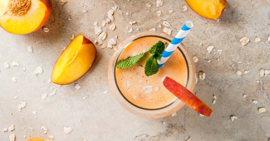 Peach smoothie on table, cut up peaches on the table