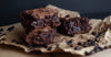 Fudgy brownies on parchment paper, with chocolate chips sprinkled around