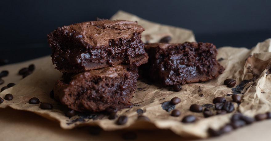Fudgy brownies on parchment paper, with chocolate chips sprinkled around