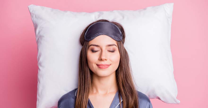 Woman sleeping on pillow, with eye mask on her forehead