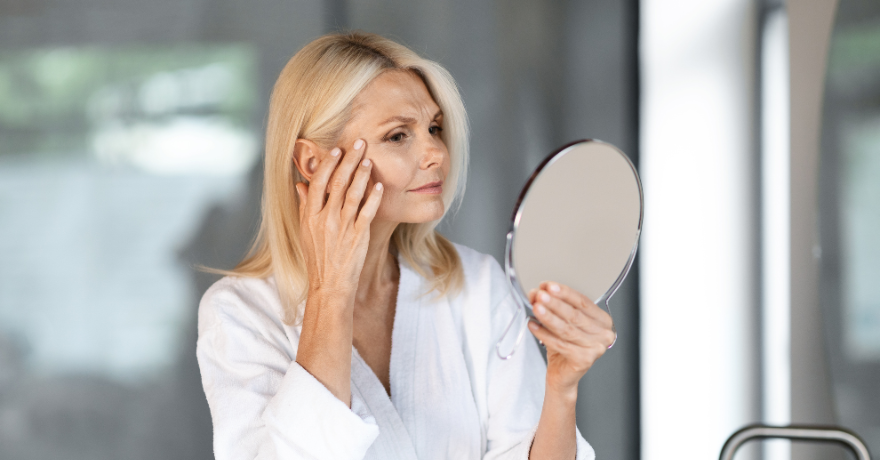 woman looking at her skin in the mirror