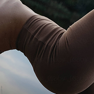 Close-up of a person's leg wearing brown leggings with a blurred natural background